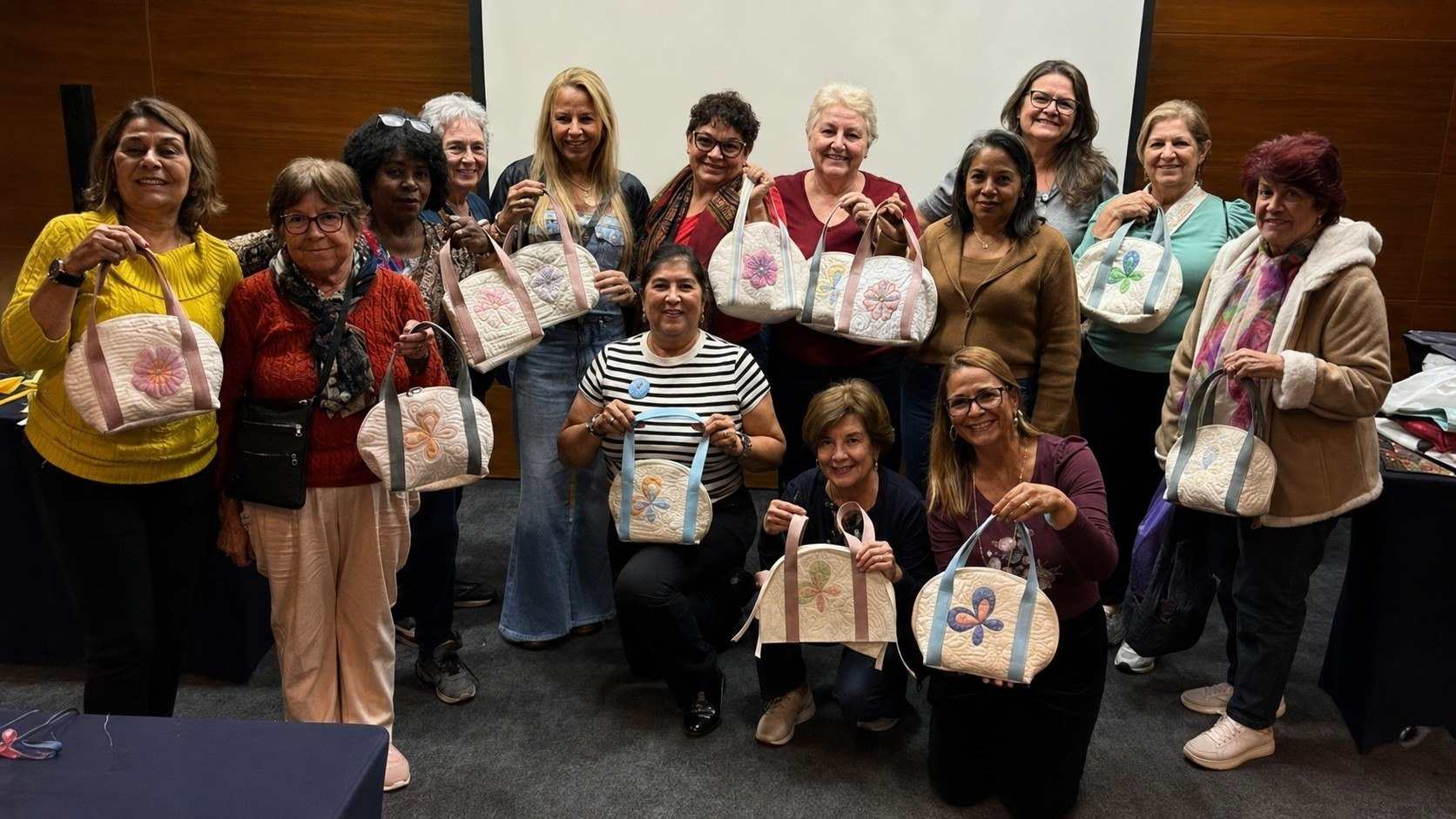 Turma de alunas da Márcia, cada uma segurando a bolsa quiltada que fez na aula